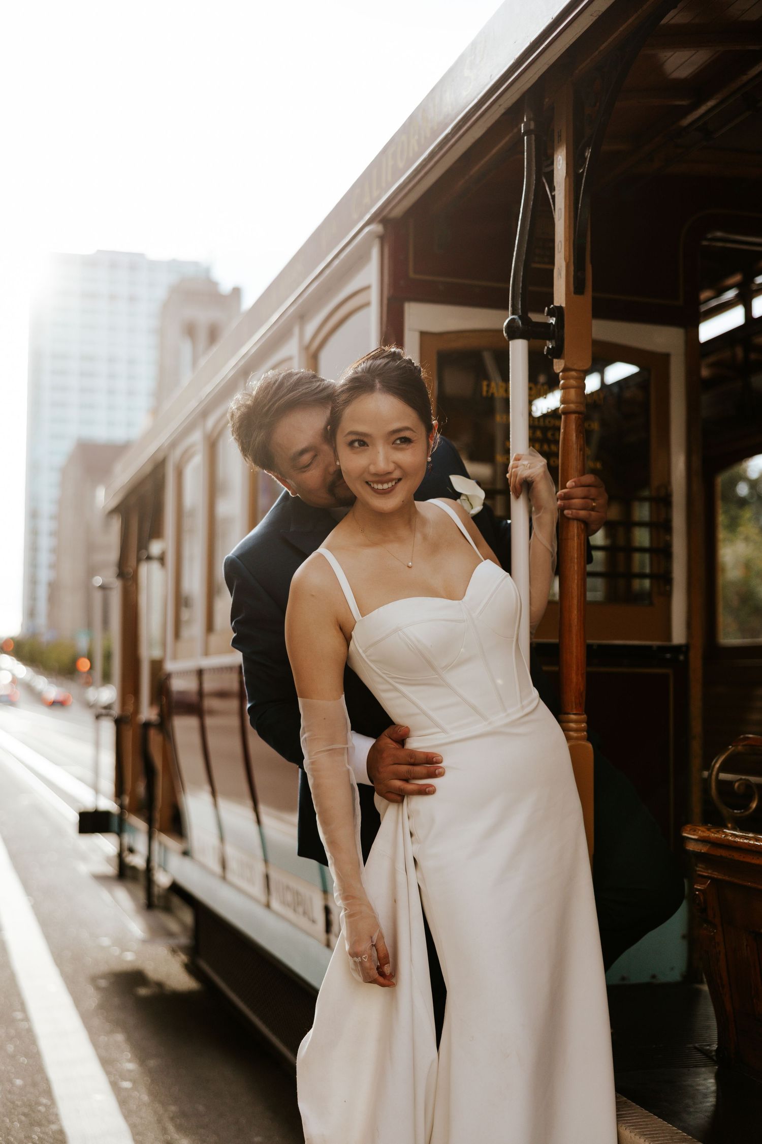 candid couple hanging off the side of a cable car in san francisco during their elopement day