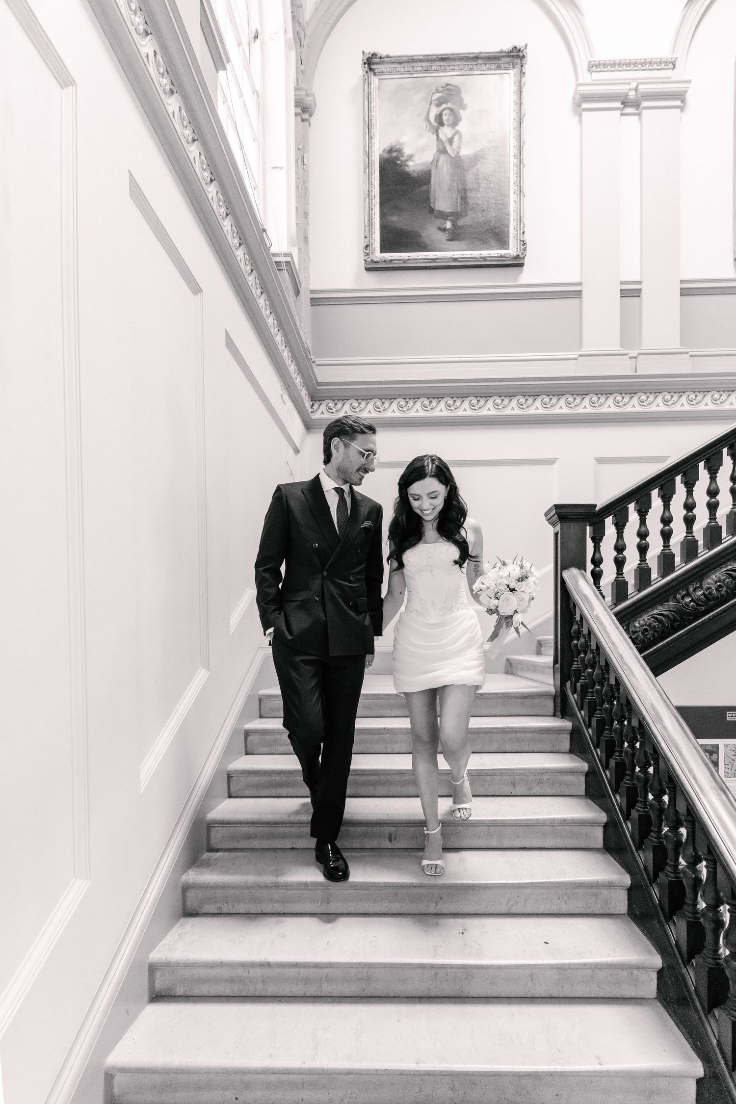 Black and white photo of a bride and groom posing on a path outdoors on their wedding day.