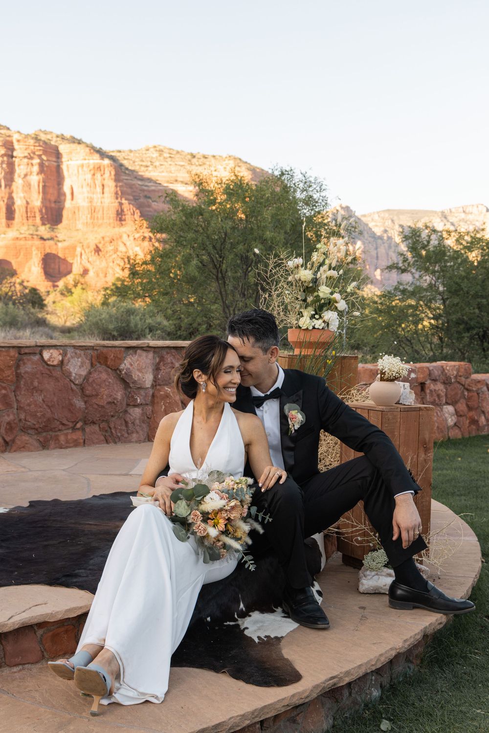 Bride and groom sitting together at a stunning Sedona Arizona wedding venue with red rock canyon views at sunset.
