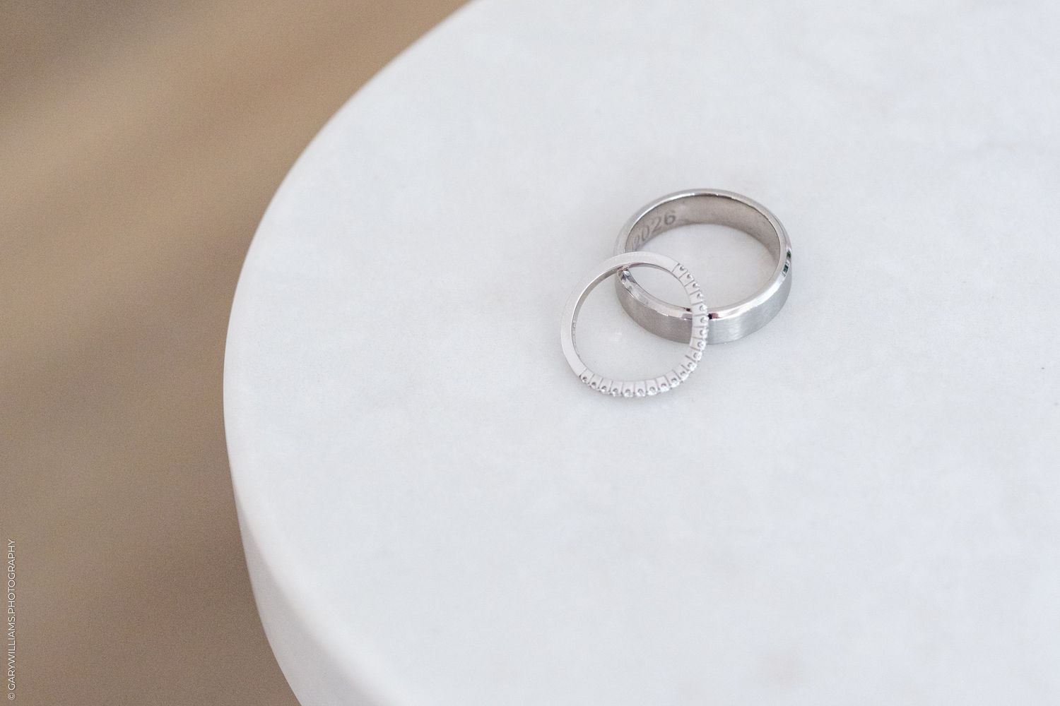 Two silver wedding rings resting on a white marble surface, symbolizing love and commitment.