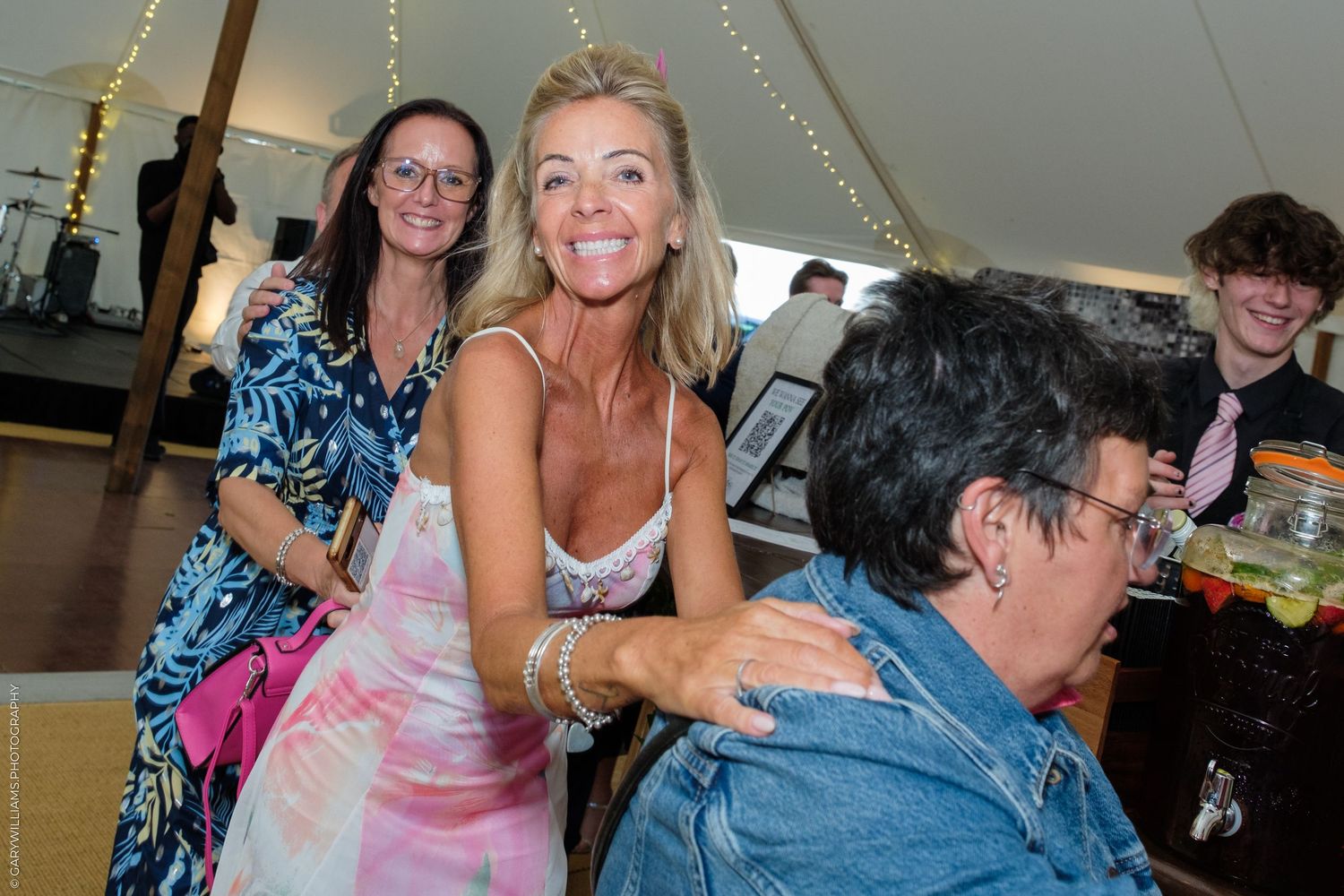 Women smiling and socializing at an elegant outdoor wedding reception under a white tent.