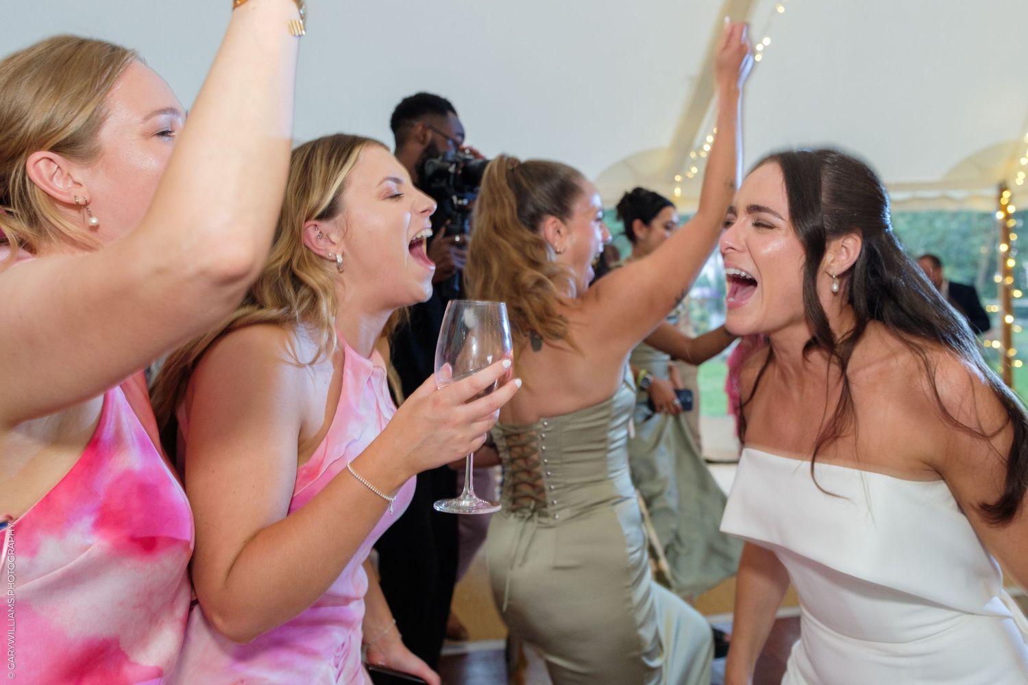 Excited women dancing and celebrating with champagne at elegant wedding reception party.