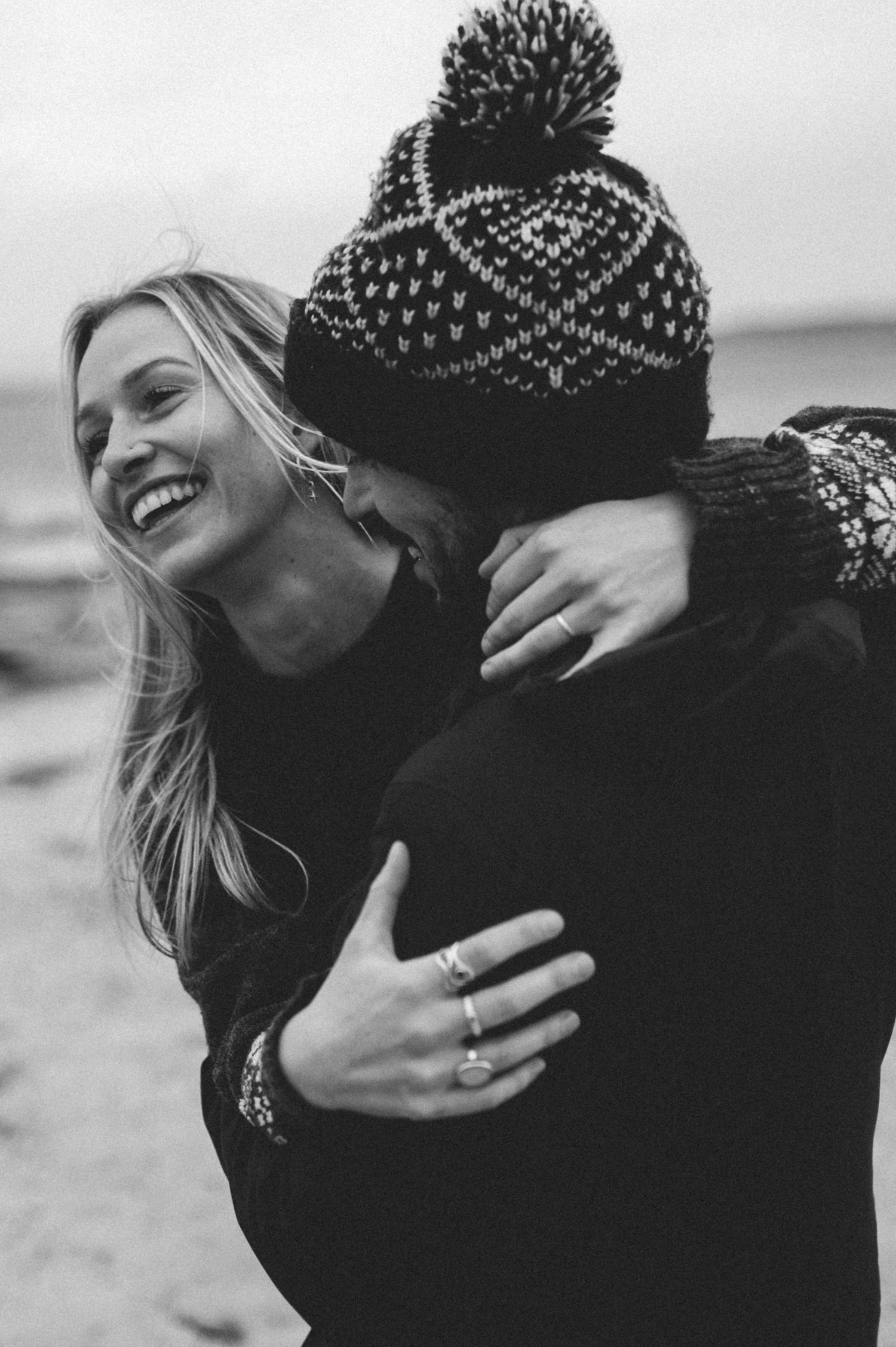 Black and white portrait of couple embracing outdoors in winter attire.