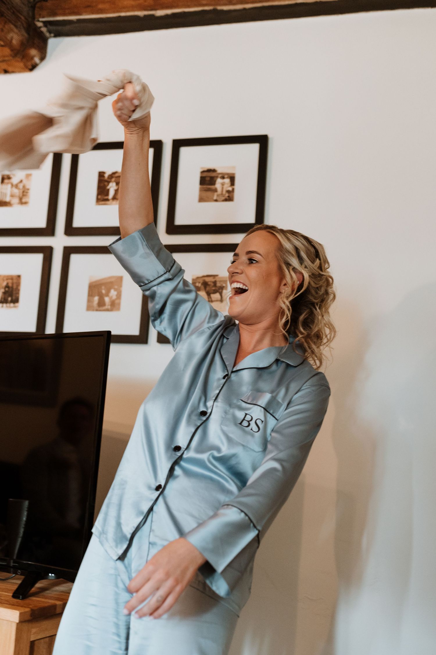 Bride in monogrammed blue satin pajamas laughing