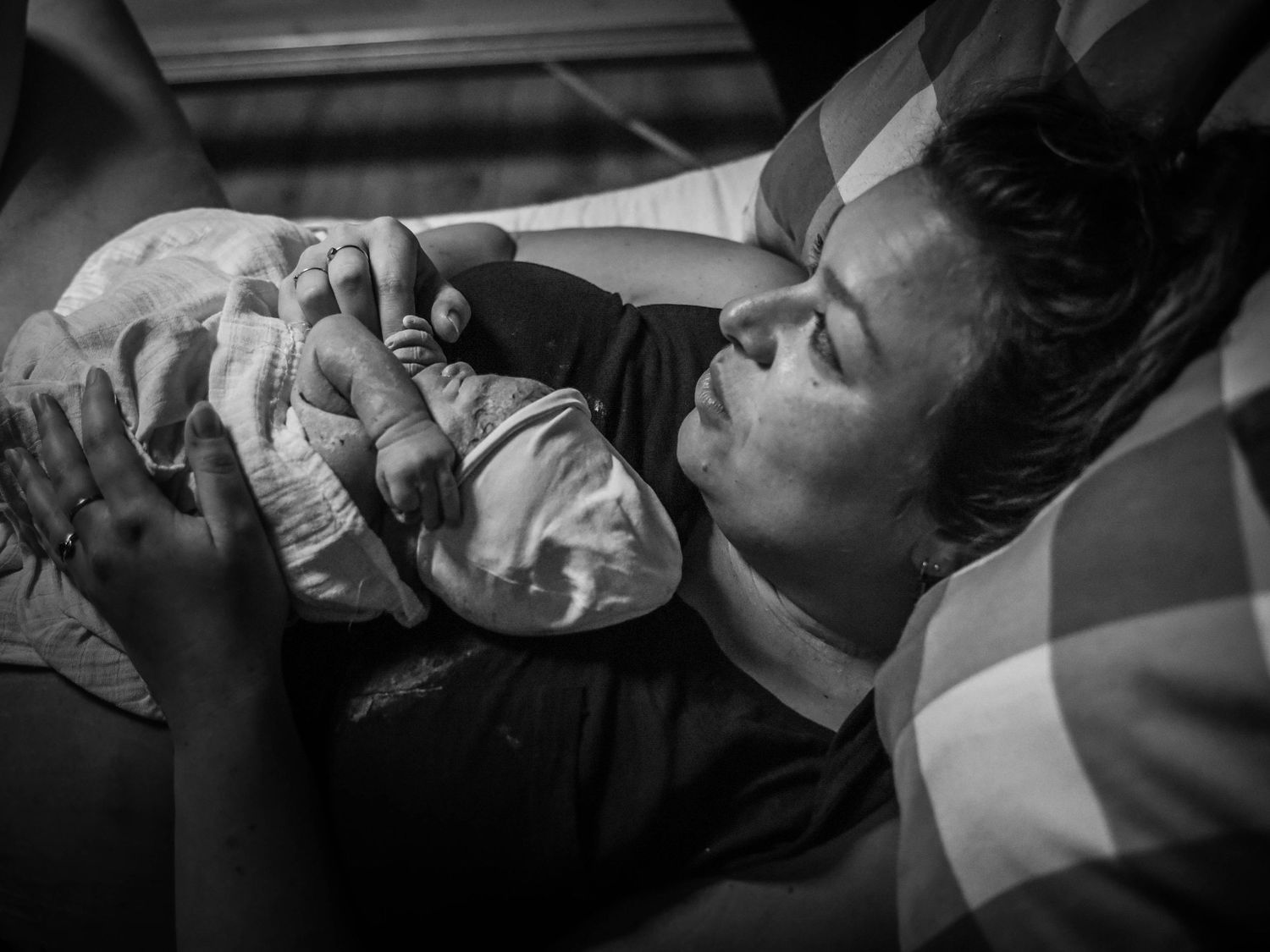 Black and white photo of a mother tenderly holding her newborn baby after childbirth.