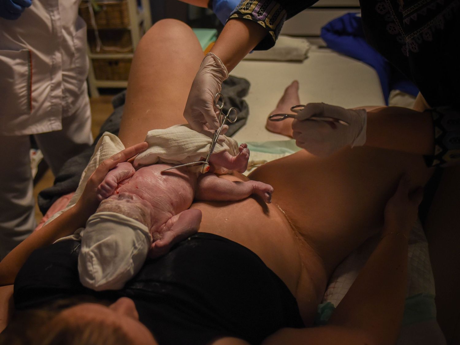Medical staff attending to a newborn baby immediately after birth in a delivery room.