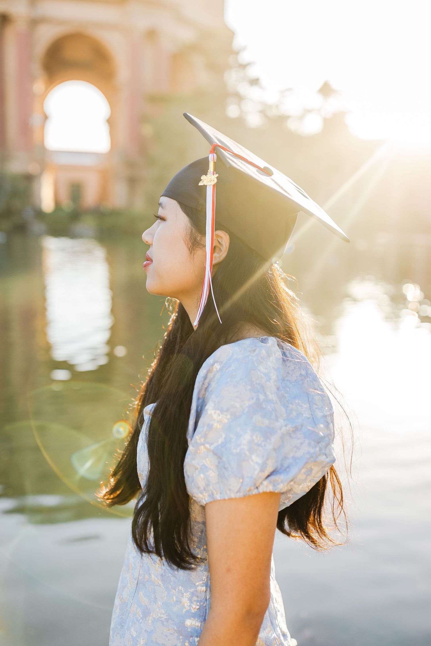 Woman posing by a serene lagoon at the Palace of Fine Arts in San Francisco during golden hour.