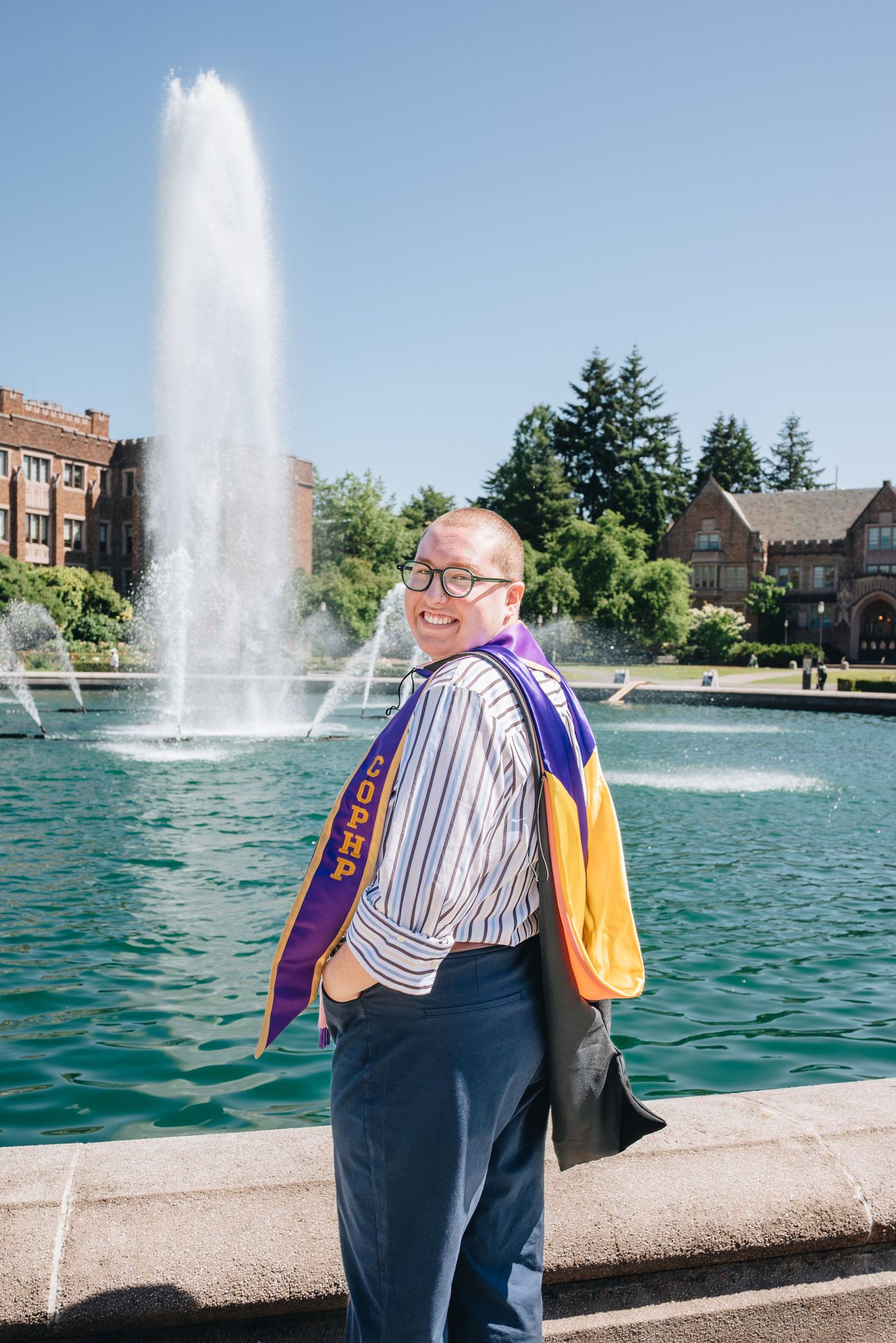 University of Washington graduate posing in front of Drumheller Fountain.