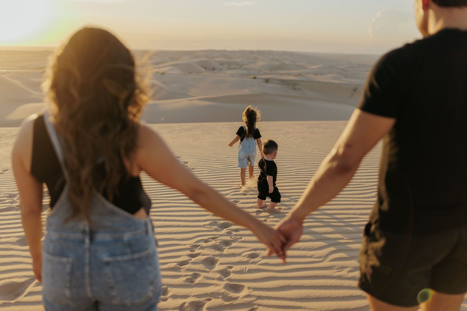 Family of four posing outdoors in desert landscape, parents and two children smiling in casual attire.