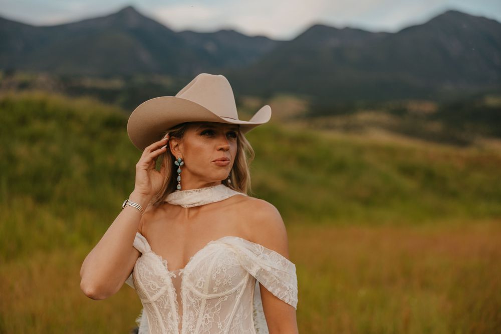 Bride shows of her wedding dress and Stetson Cowboy hat in Paradise Valley, Montana at Copper Rose Ranch captured by Wedding Photographer