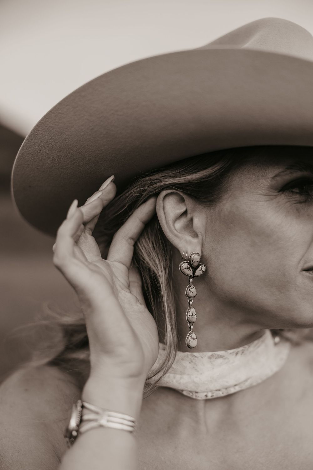 Bride shows off her turquoise earrings and Stetson western cowboy hat at Copper Rose Ranch in Pray, Montana by local Emigrant Photographer