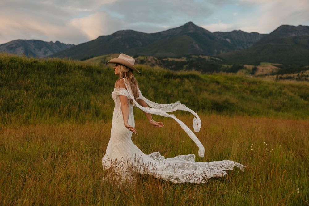 Bride shows of her wedding dress and Stetson Cowboy hat in Paradise Valley, Montana at Copper Rose Ranch captured by Wedding Photographer