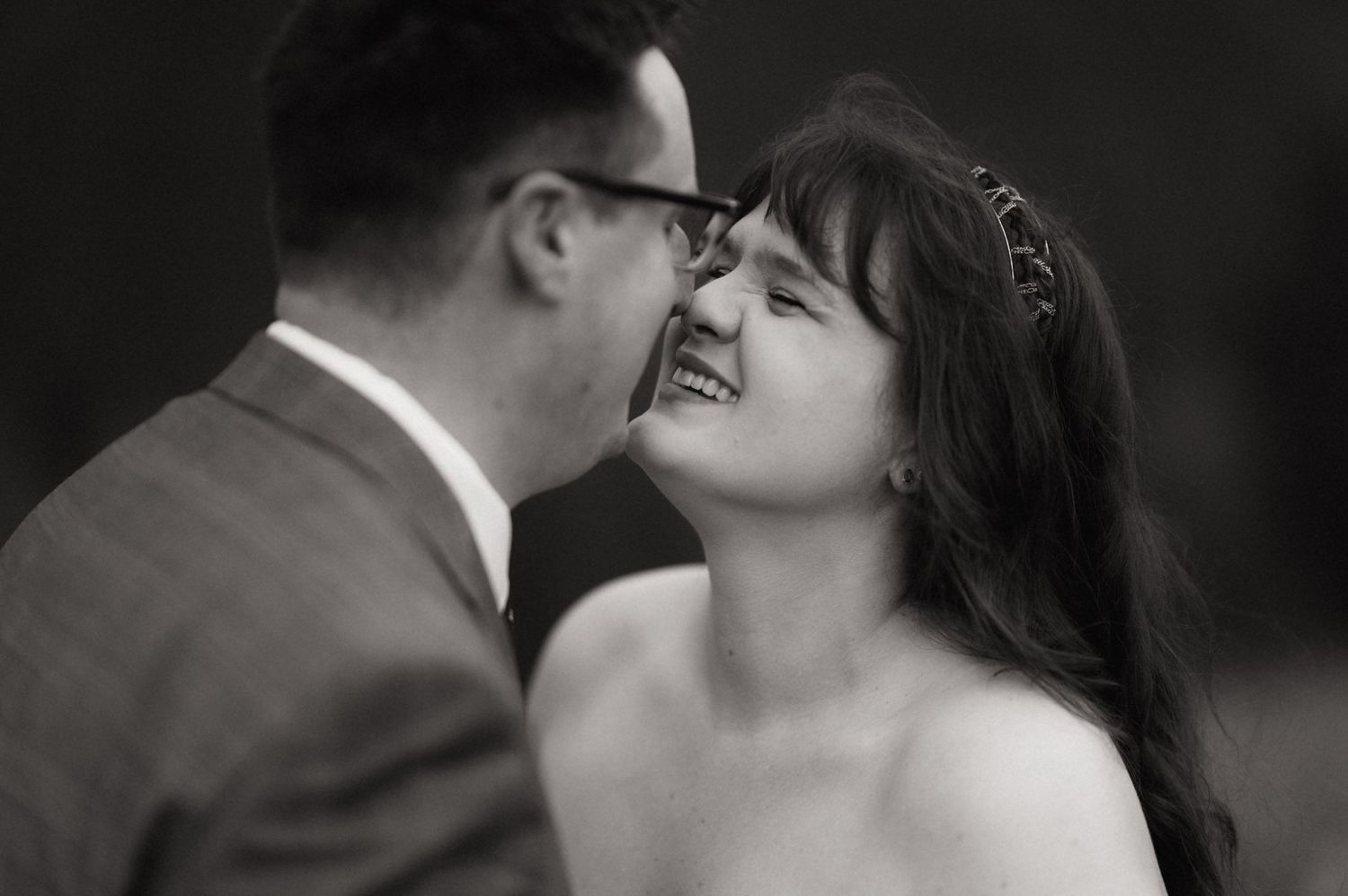 Black and white wedding photo of a smiling bride and groom sharing an intimate moment.