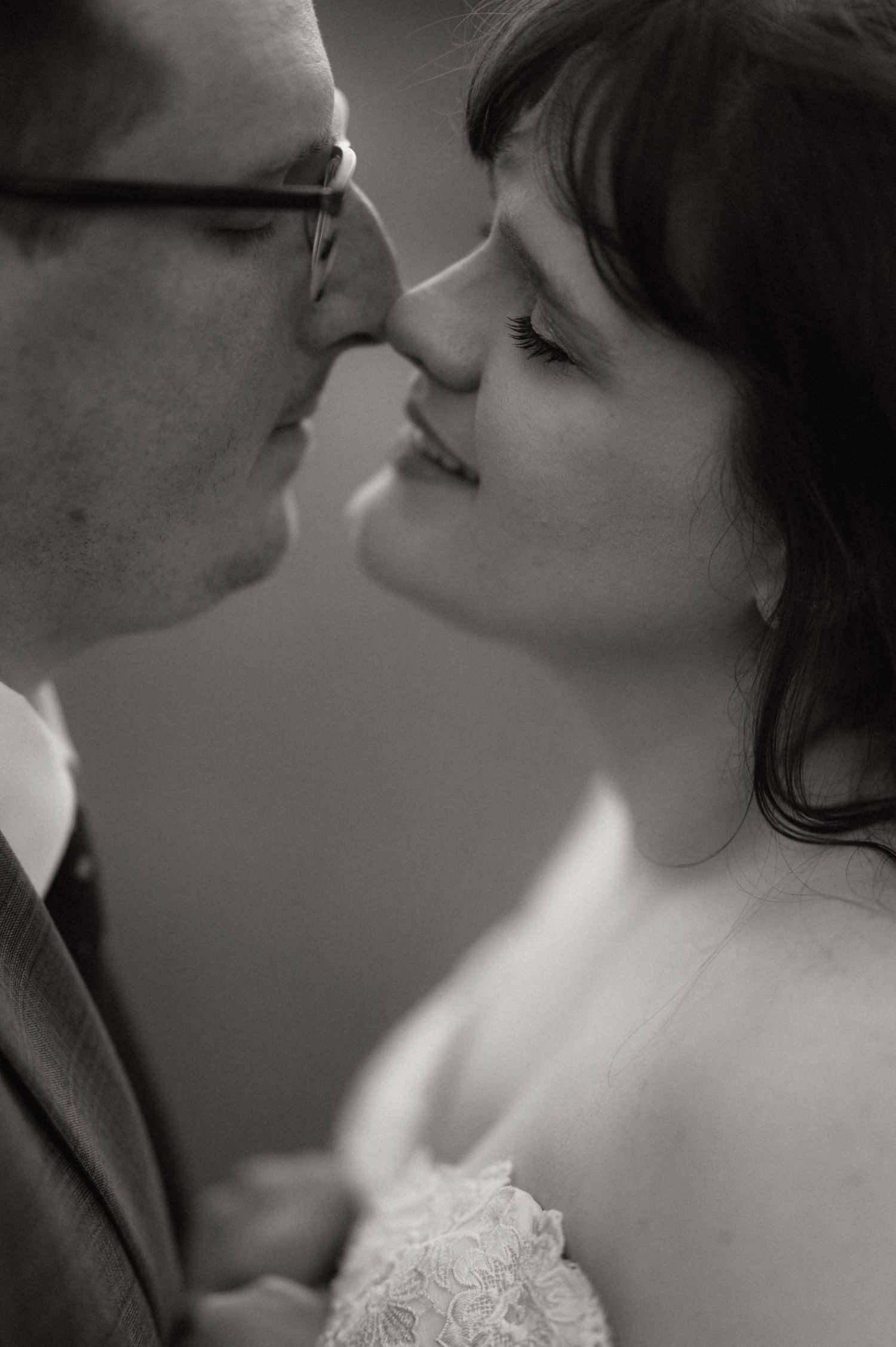 Black and white close-up of a bride and groom sharing a romantic kiss on their wedding day.
