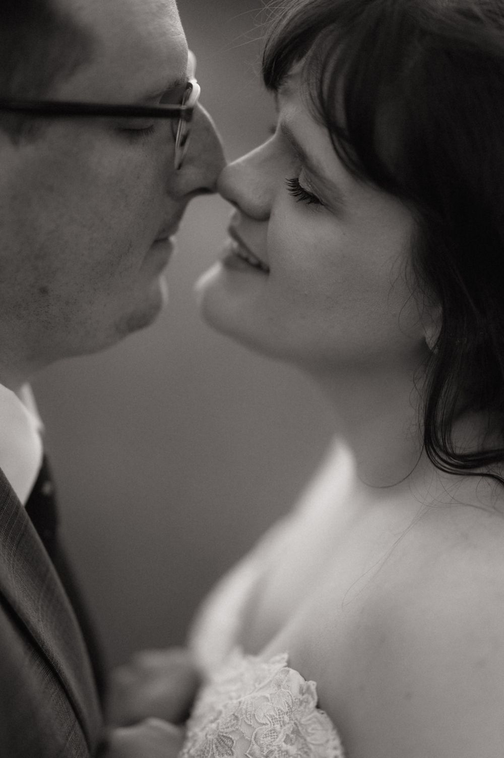 Black and white close-up of a bride and groom sharing a romantic kiss on their wedding day.
