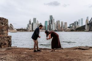 Couple sharing a romantic moment on Sydney Harbour foreshore with Opera House and city skyline views.