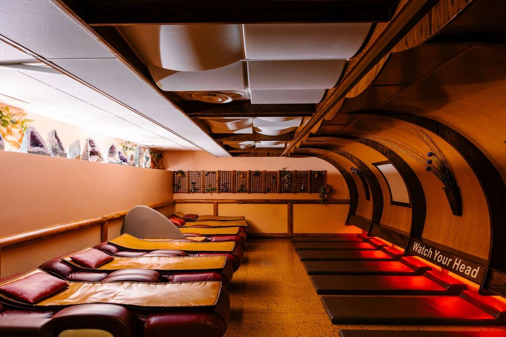 Converted London Underground tunnel lounge with mattress seating, arched walls, and a Watch Your Head sign.