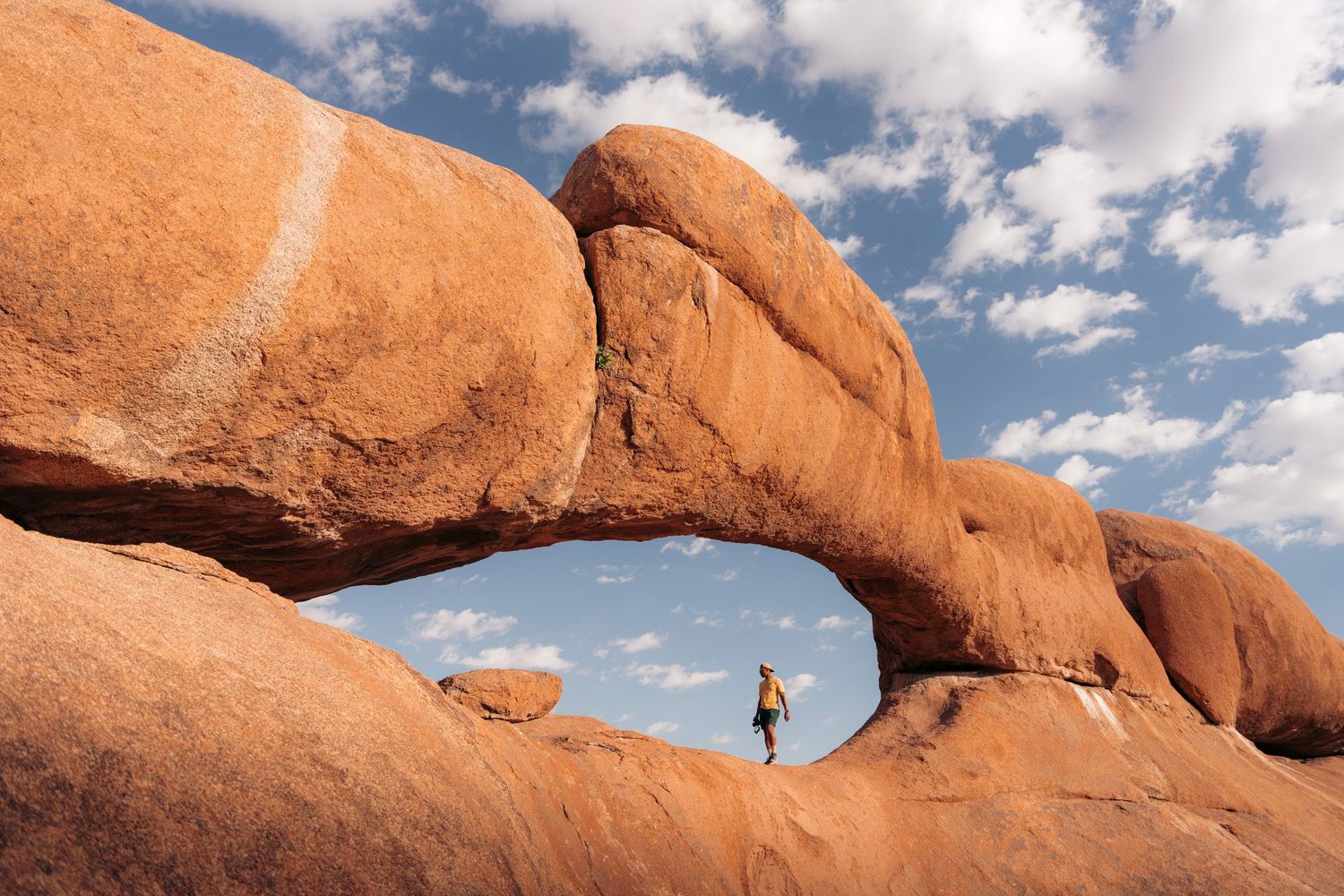 the arch, un homme marche dans une immense cavité rocheuse à spitzkoppe