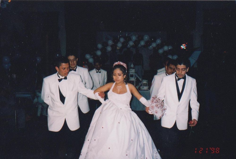 quince in white ball gown walks with groomsmen in white tuxedos at a formal wedding reception. Minneapolis chamberlain to photographer