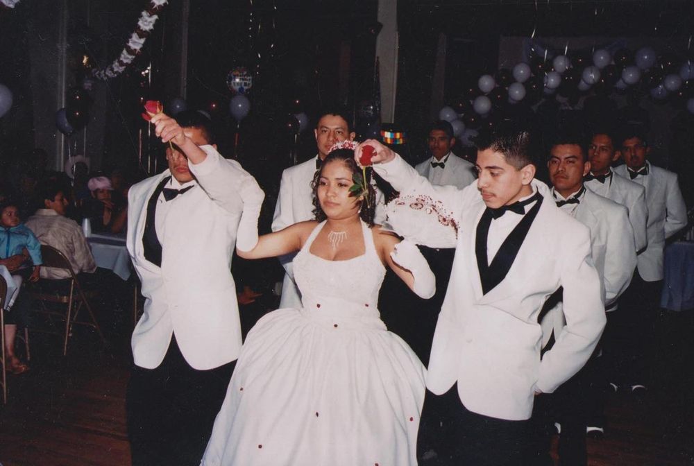 quinceañera ball gown dancing with groomsmen in white tuxedos at a wedding reception. fotografo en Minneapolis