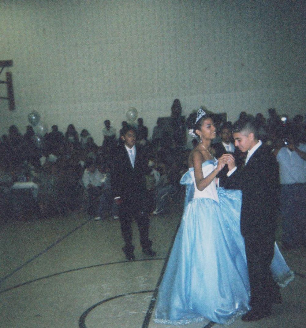A young woman in a blue ball gown and tiara dances with a man in a tuxedo at a quince. fotografo en Minnesota