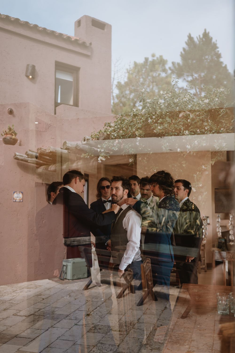 Groom and groomsmen gathered outside a pink Mediterranean villa on the wedding day.