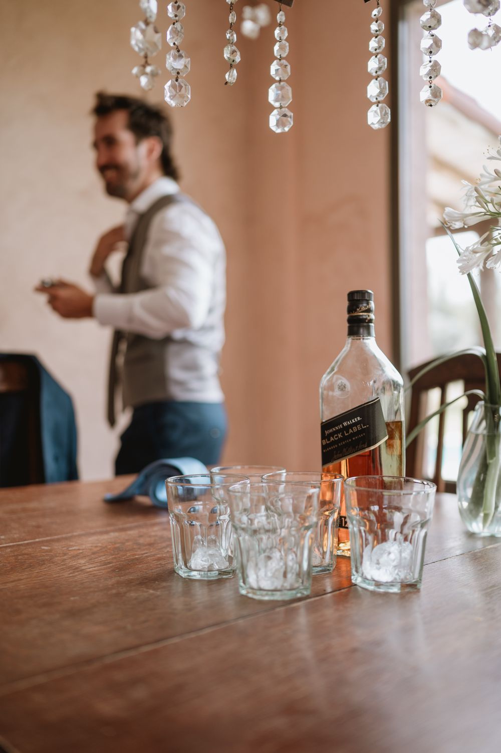 Bottle of Johnnie Walker Black Label whiskey on a table with groom in background.