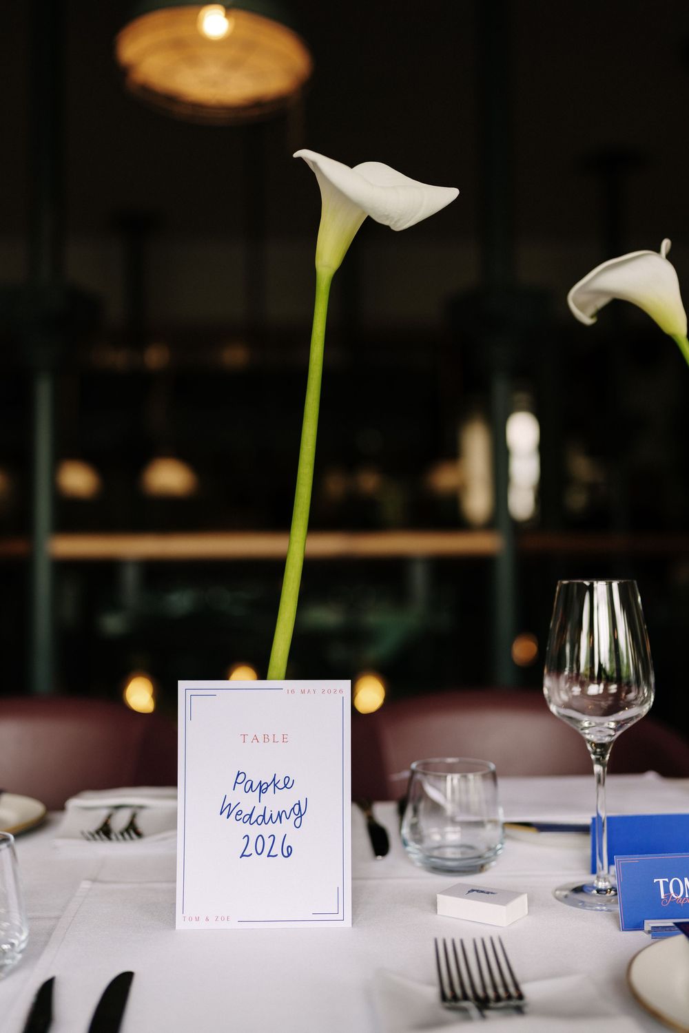Elegant wedding reception table set with white calla lilies and a place card reading Papke Wedding at Pasture Bristol Wedding