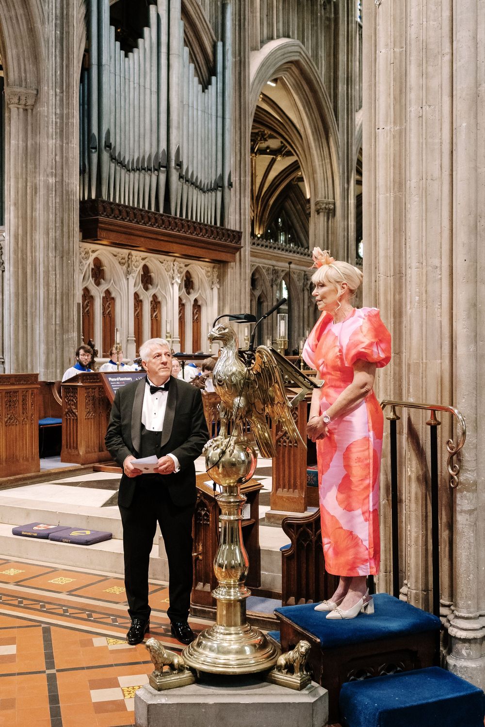 Man in tuxedo and woman in pink dress stand at ornate St Mary Redcliffe Church Bristol Wedding