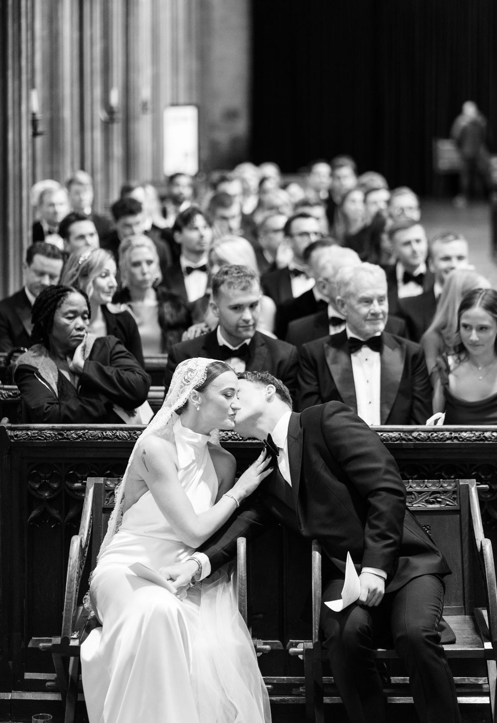 Black and white photo of a bride and groom sharing a kiss during their wedding ceremony at St Mary Redcliffe Church, Bristol Wedding