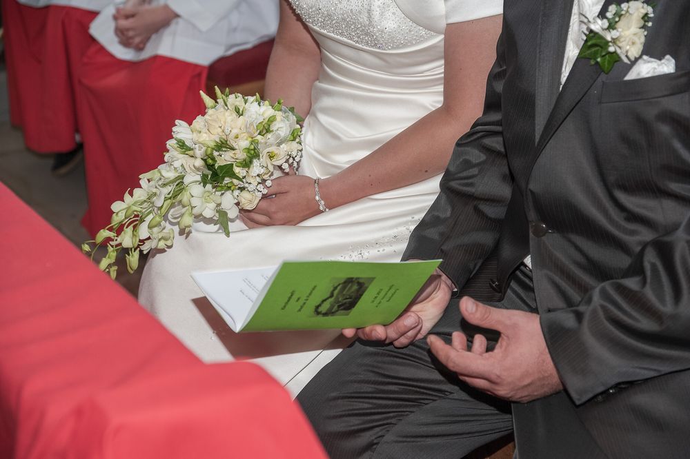 Brautpaar hält gemeinsam ein Programmheft in der Vexierkapelle bei Reifenberg. Emotionale Hochzeitsfotografie von der Lichtkapsel.