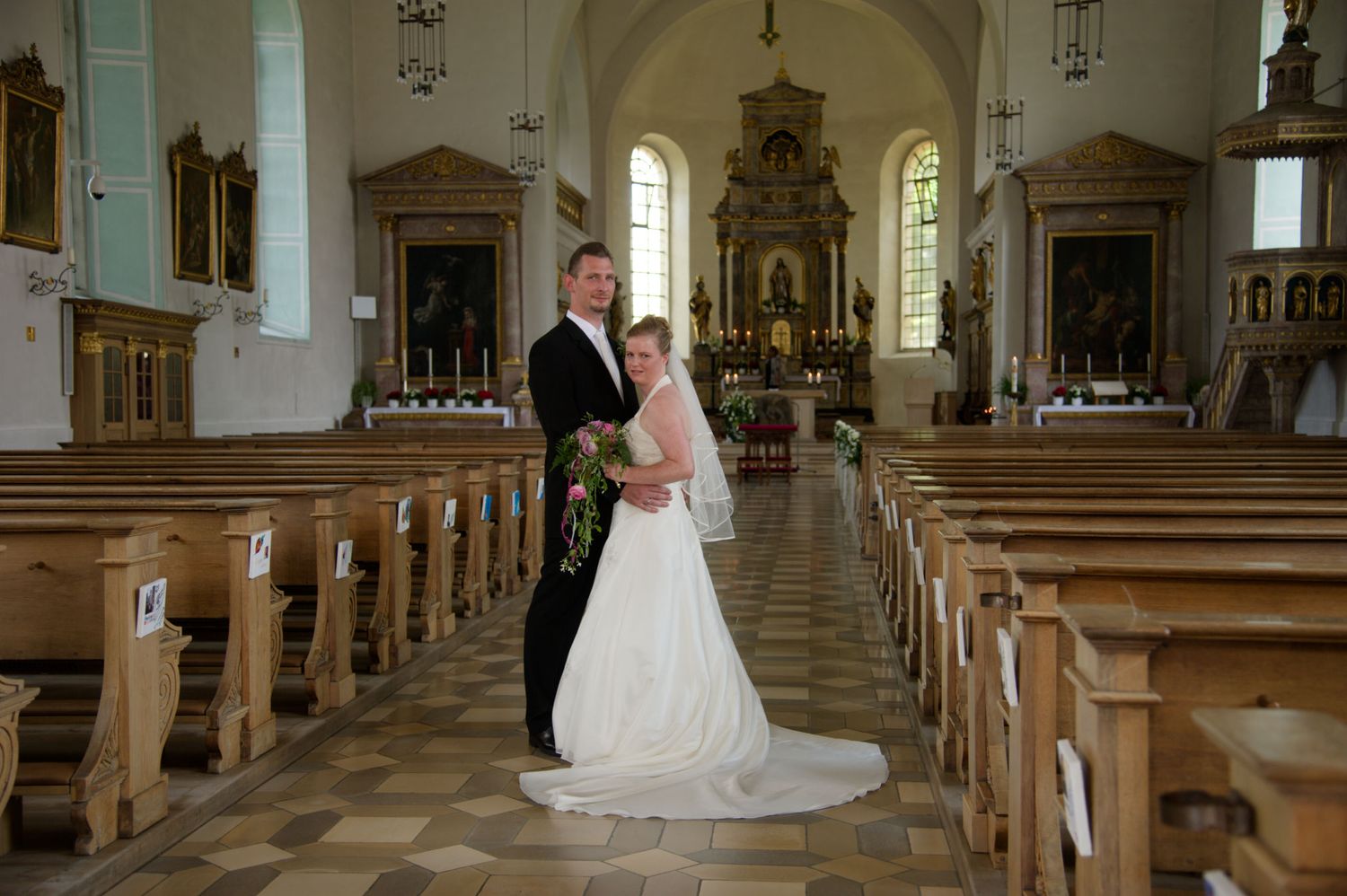 Brautpaar steht glücklich vor dem Altar bei der kirchlichen Trauung. Emotionale Hochzeitsfotografie in einer Kirche in Eggolsheim.