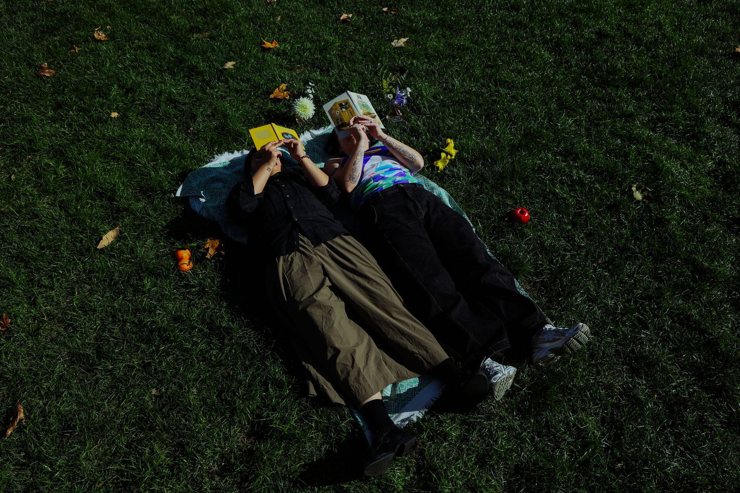 A couple picnicking in the grass, surrounded by different fruits and flowers at the Lewis MacAdams Riverfront Park in Los Angeles.