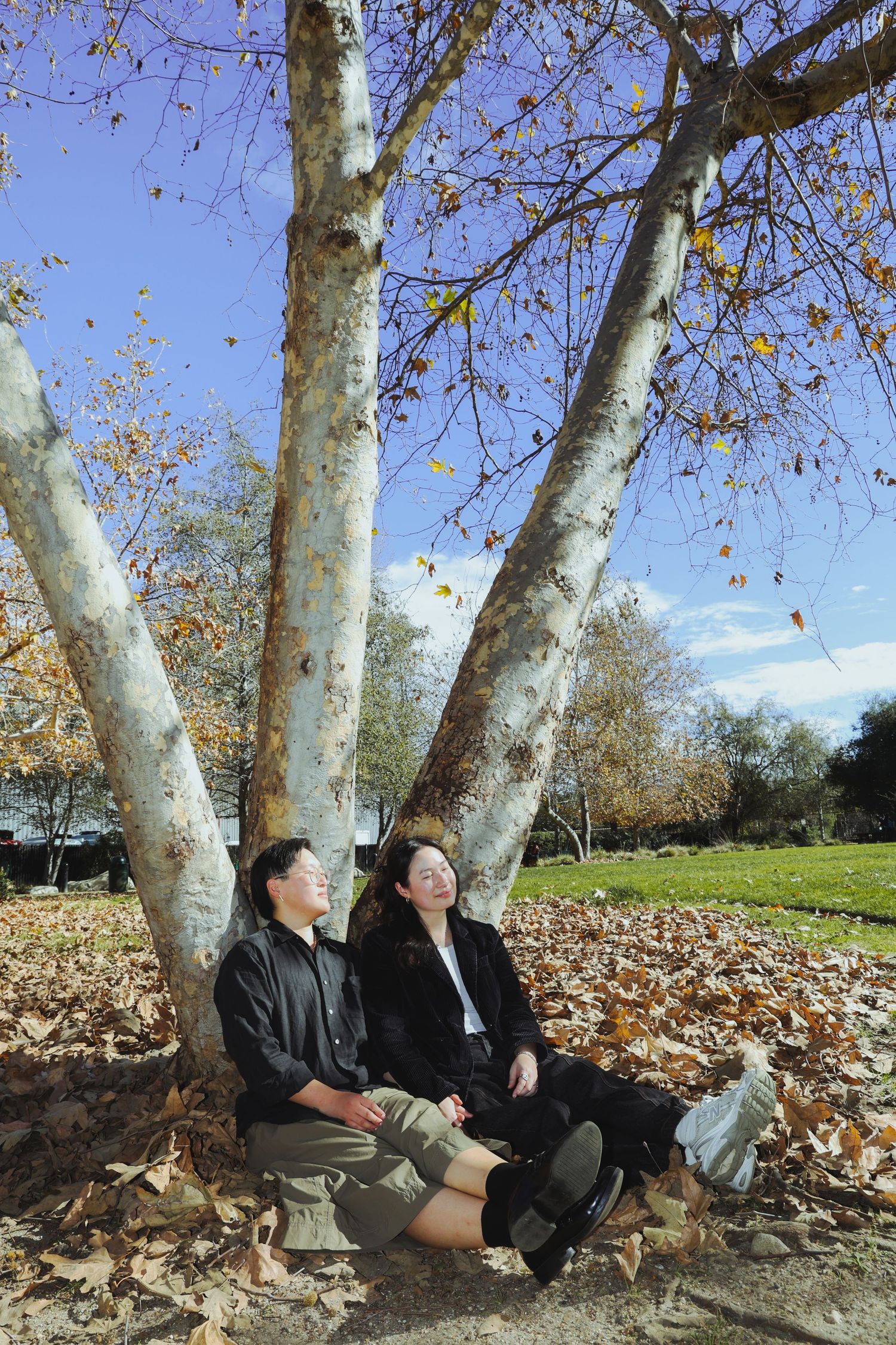 A couple picnicking in the grass, surrounded by different fruits and flowers at the Lewis MacAdams Riverfront Park in Los Angeles.