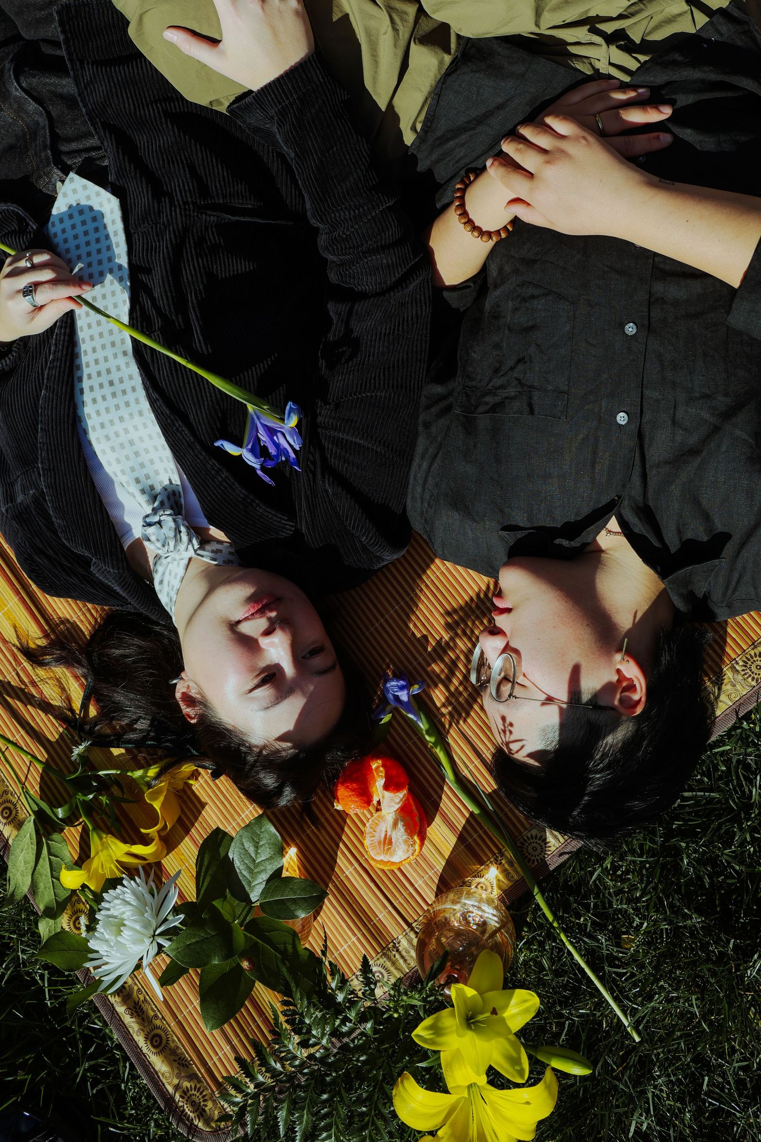 A couple picnicking in the grass, surrounded by different fruits and flowers at the Lewis MacAdams Riverfront Park in Los Angeles.