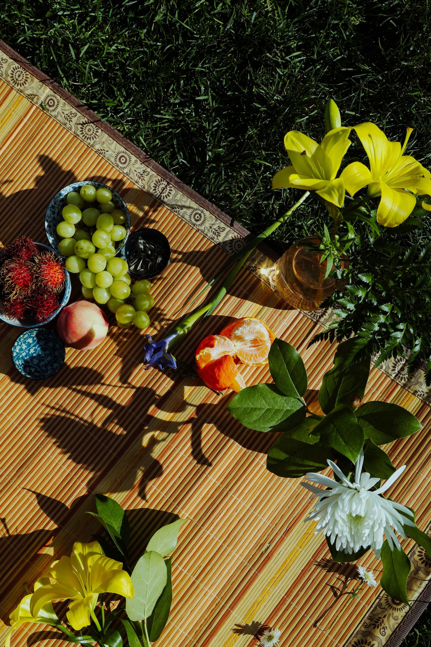 A couple picnicking in the grass, surrounded by different fruits and flowers at the Lewis MacAdams Riverfront Park in Los Angeles.