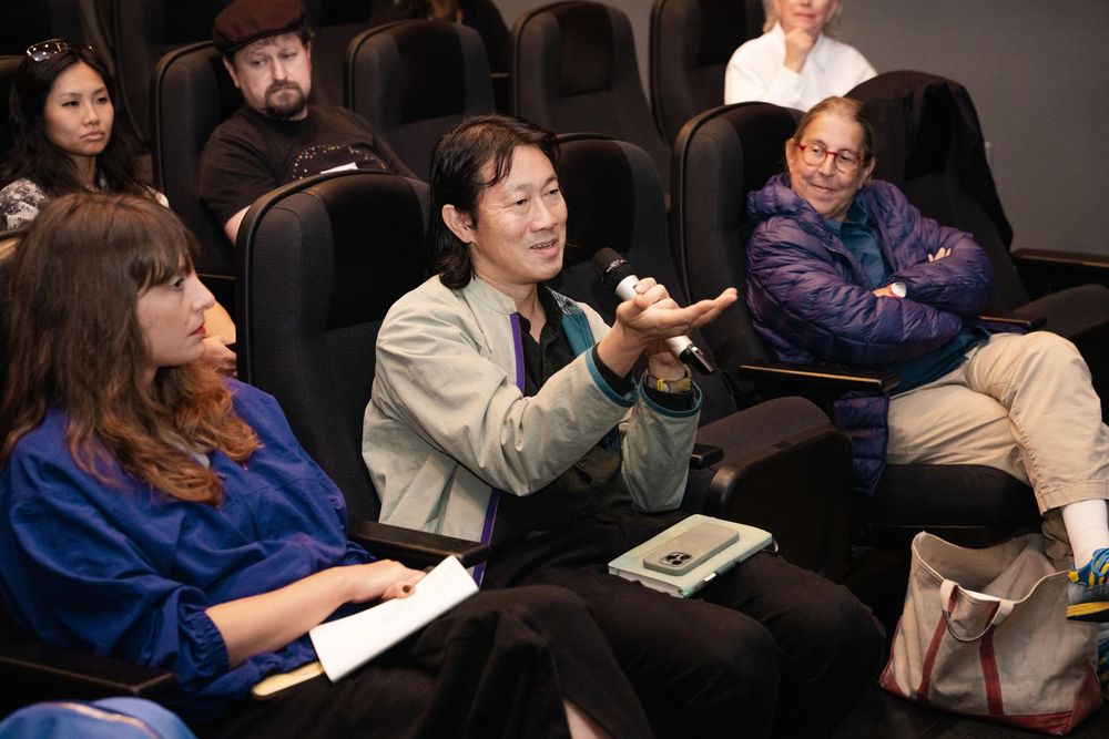 People seated in a theater during a Q&A session, with a person holding a microphone speaking to the audience.