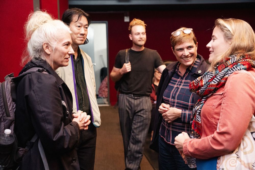 Five people engaged in conversation at an indoor social gathering event.