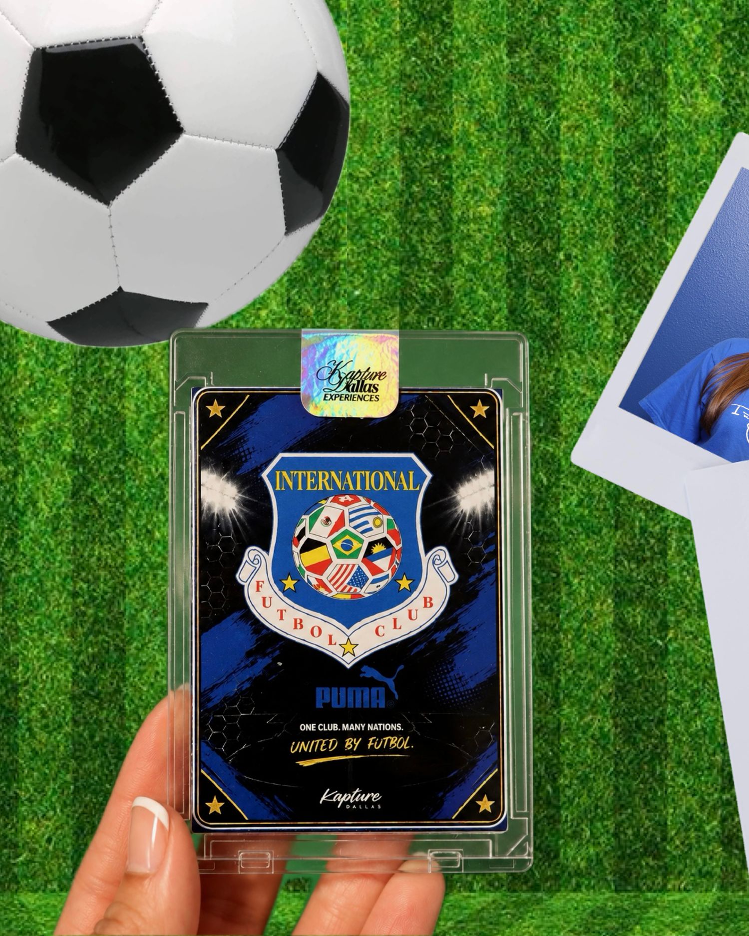 Hand holding an International Futbol Club trading card in acrylic case on grass with soccer ball.