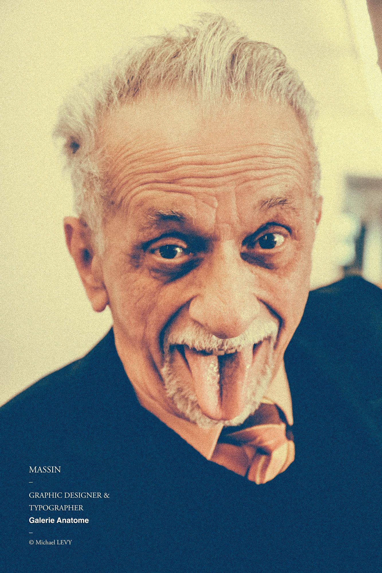 Elderly man with white hair and mustache making a funny face, sticking out his tongue playfully.