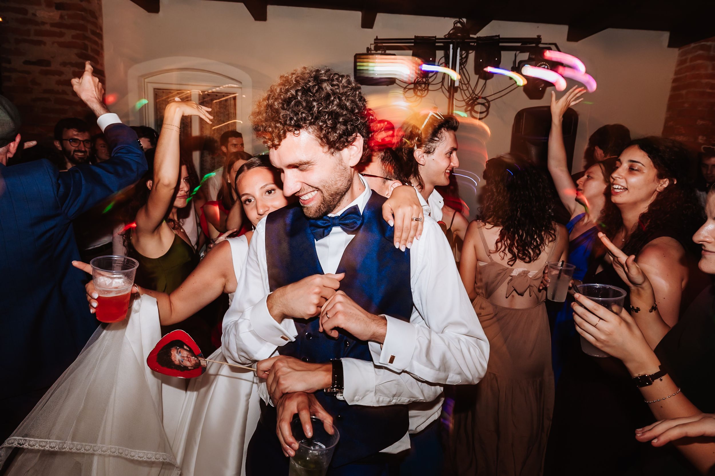 Bride and groom dancing joyfully with guests at a lively wedding reception party.