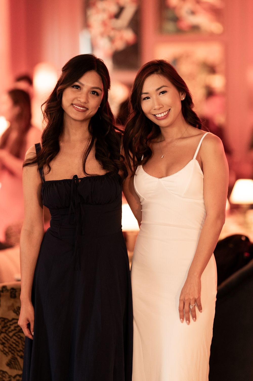 Two elegant women posing at an upscale event, wearing black and white formal dresses.