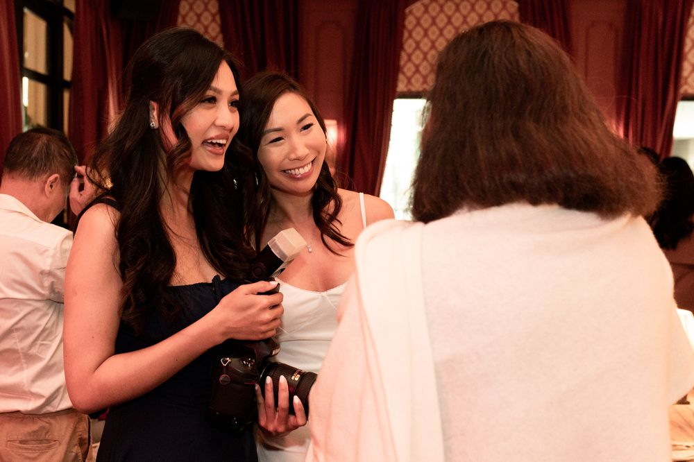 Two women in elegant dresses laughing and socializing at a formal event.
