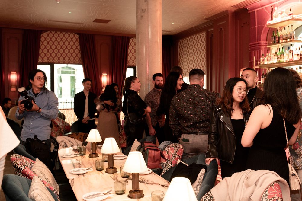 Guests mingling at an elegant restaurant event with warm lighting and decorated tables.