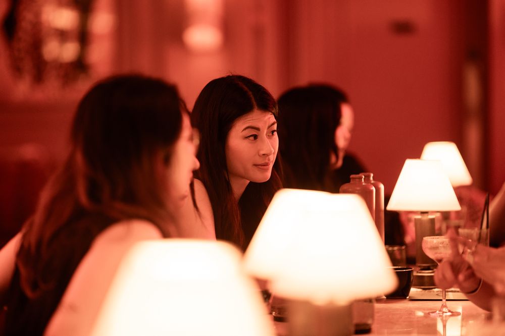 Women dining at a warmly lit restaurant with glowing table lamps and red ambient lighting.