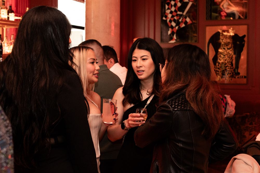 Group of young women socializing and mingling at a dimly lit party or event.