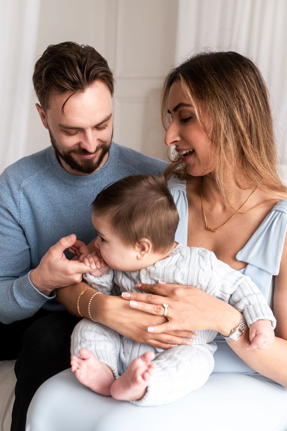 Happy young couple smiling and bonding with their infant baby in a bright cozy setting.