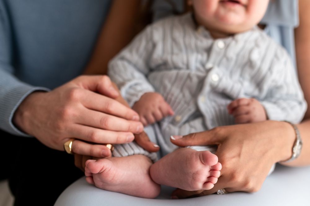 Close-up of parents hands gently holding a newborn babys tiny feet and body.