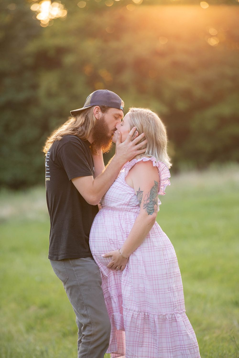 A tender moment between a couple embracing in a sunlit field at golden hour.