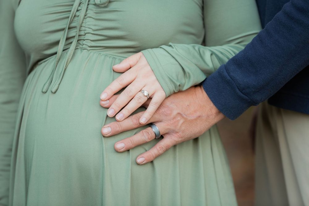 A row of pregnant women in green shirts stand side by side showing their baby bumps.